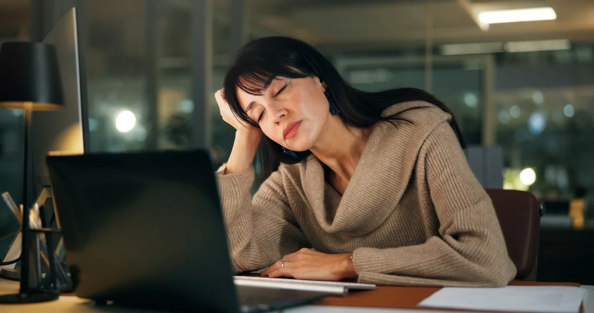 Tired woman sleeping at her office desk in front of a laptop.